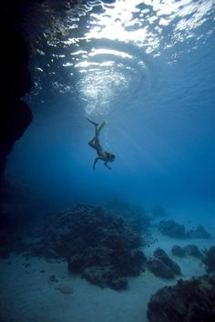 a person swimming in the ocean with rocks and water around them on a sunny day