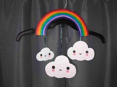 a rainbow and cloud mobile hanging from a curtain with black curtains in the back ground