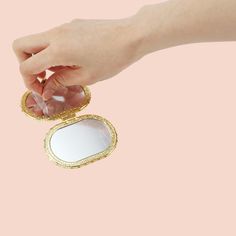 a person holding a compact mirror in their hand