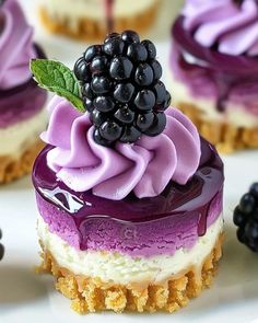 there are several desserts with purple icing and blackberries on the top one