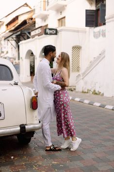 a man and woman standing next to a white car