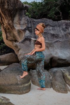 a woman is sitting on some rocks in the sand