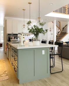 a kitchen with an island in the middle and stairs leading up to the second floor