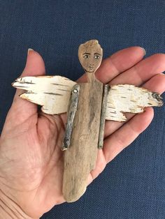 a person holding a piece of driftwood with a wooden angel on it's back