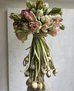 a bunch of flowers that are on top of a piece of wood and some garlic