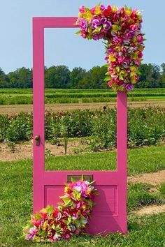 a pink frame with flowers on it sitting in the middle of a grass covered field