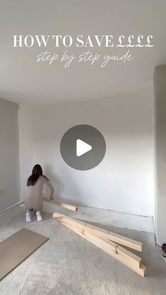 a woman kneeling down on the floor in front of a wall with some unfinished boards