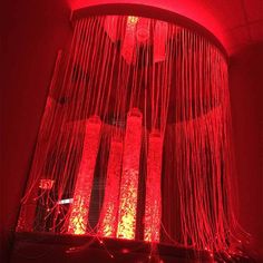 a red light hanging from the ceiling in front of a chandelier with lights on it