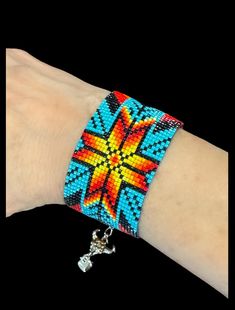 a hand with a bracelet on it that has an orange, yellow and blue design