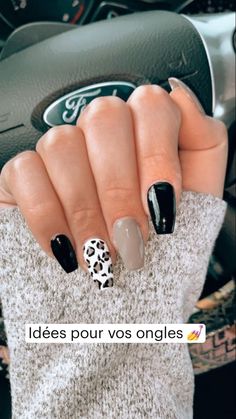 a woman's hand with black and white nail polish on her nails, in front of a car steering wheel