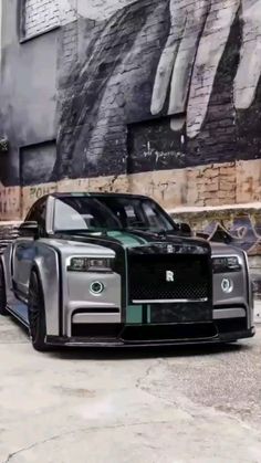 a black and silver car parked in front of a building with graffiti on the walls