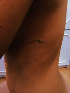 a woman with a small wave tattoo on her side ribcage and the word love written in cursive writing