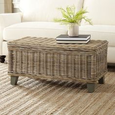 a wicker coffee table sitting on top of a rug next to a white couch