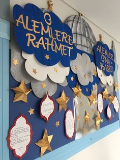 a bulletin board is decorated with gold stars and blue paper clouds that read, alemer rahmmet