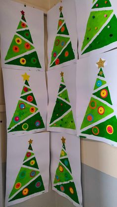 four christmas trees made out of white paper and colored circles on the bottom, with gold stars