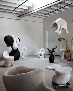 various sculptures are displayed in an empty room with white walls and exposed pipes above them