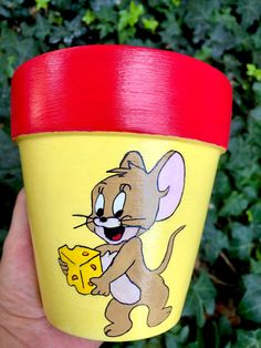 a hand holding a yellow cup with a cartoon mouse on it