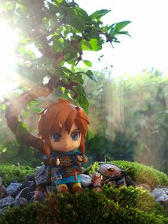 a figurine sitting on top of a pile of rocks next to a tree