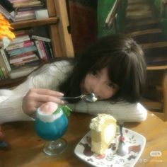 a woman sitting at a table with a fork in her mouth and a piece of cake on the plate