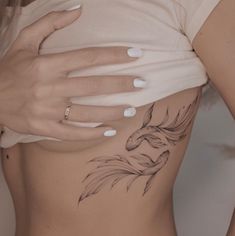 a woman's stomach with a tattoo design on the side and her hands behind her back