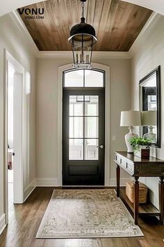 an entryway with a black door and white walls, wooden floors and a rug on the floor