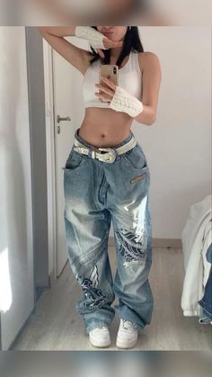 a woman taking a selfie with her cell phone in front of her face and wearing ripped jeans