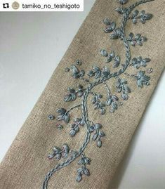 a close up of a tie on a table with embroidered flowers and leaves in it