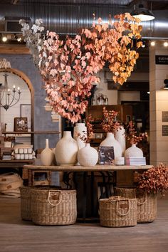 an arrangement of vases and flowers on a table in a room with other items