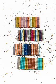 three rows of colorful bracelets on a white surface with confetti scattered around them