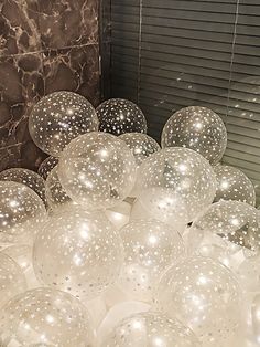 some white balloons are sitting in front of a wall with black and white marble walls