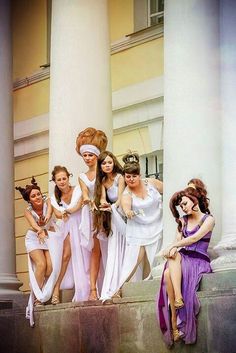 four women in white dresses are sitting on the steps and one woman is standing behind them