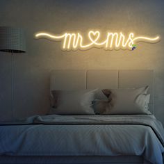 there is a neon sign that says mom on the wall above a bed with pillows