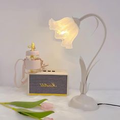 a lamp that is sitting on top of a table next to a cake and flowers