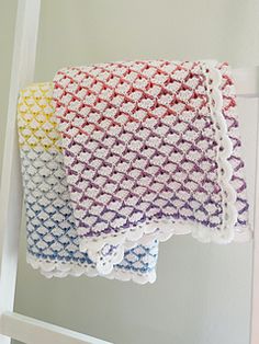 two crocheted towels hanging on a ladder next to each other in different colors