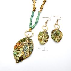 Fun and lightweight boho jewelry pendant necklace and earring set features handpainted, realistic and textured leaves made with polymer clay and resin. The pendant hangs on a knotted macrame cord accented with irregular colored seed beads - perfect to wear with your favorite  t- shirts or casual outfits! Let's welcome spring and summer with these whimsical, boho chic accessories. The clay beads are hand painted, baked, sanded, buffed, and sealed with resin for protection.  Findings: plated metal Bohemian Beaded Polymer Clay Jewelry, Beaded Bohemian Polymer Clay Necklaces, Bohemian Beaded Polymer Clay Necklaces, Bohemian Polymer Clay Pendant Jewelry, Bohemian Gold Polymer Clay Jewelry, Gold Bohemian Polymer Clay Jewelry, Handmade Nature-inspired Polymer Clay Jewelry, Bohemian Polymer Clay Jewelry For Festivals, Handmade Bohemian Polymer Clay Necklace