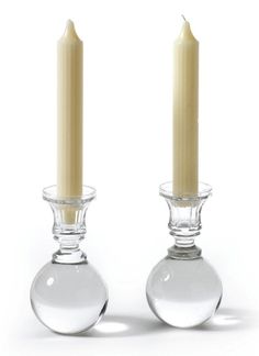 two clear glass candlesticks sitting next to each other