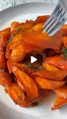 a white plate topped with cooked carrots and a fork