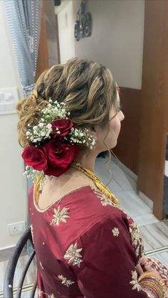 a woman with flowers in her hair sitting on a chair