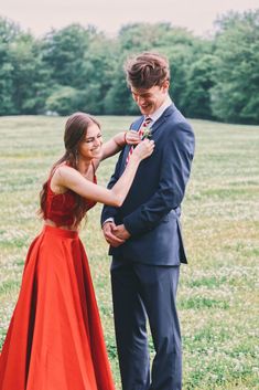 a man and woman in formal wear standing next to each other on a grass field