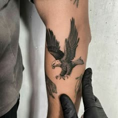 a man with a tattoo on his arm holding an eagle in front of the camera