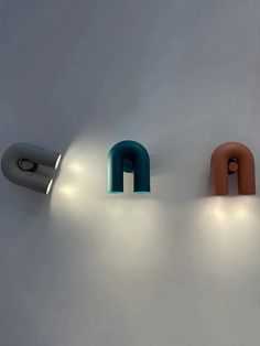 three lights that are on the side of a wall next to each other in different colors