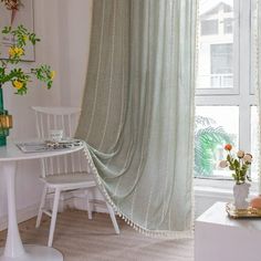 a white table and chair in front of a window with curtains on the windowsill