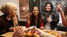 four women are standing around a table eating food