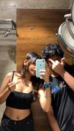 a man and woman taking a selfie in front of a mirror with their cell phones