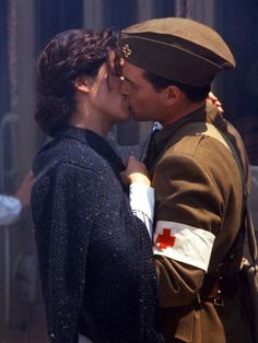 a man in uniform kissing a woman on the cheek