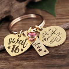 two heart shaped keychains with names on them sitting on top of a wooden table