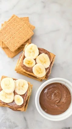 peanut butter and banana slices on crackers next to a small bowl of chocolate pudding