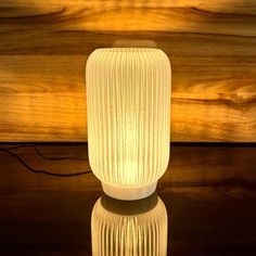 a white lamp sitting on top of a table next to a wooden wall and floor