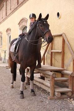 a man riding on the back of a brown horse next to a wooden bench and stairs