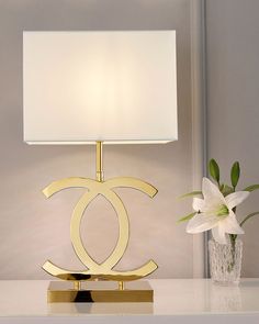 a lamp on a table next to a vase with white flowers and a flower pot